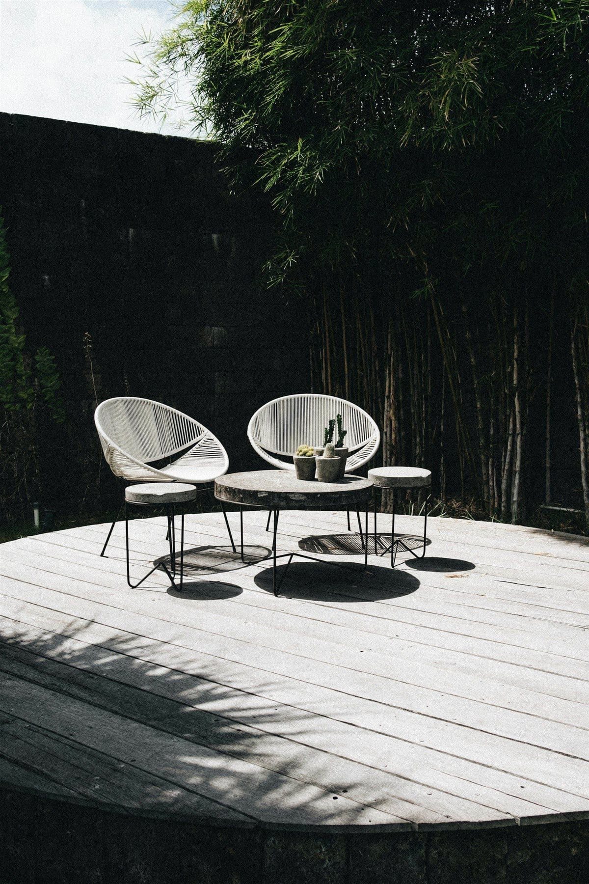 Wooden backyard deck with outdoor furniture, surrounded by trees